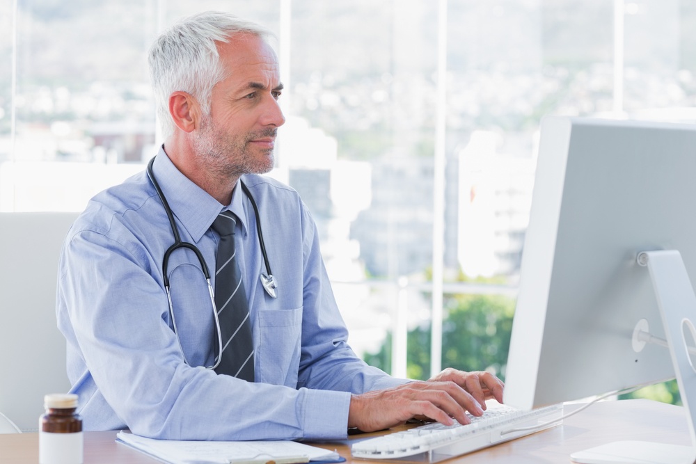Doctor typing on his computer in the office.jpeg